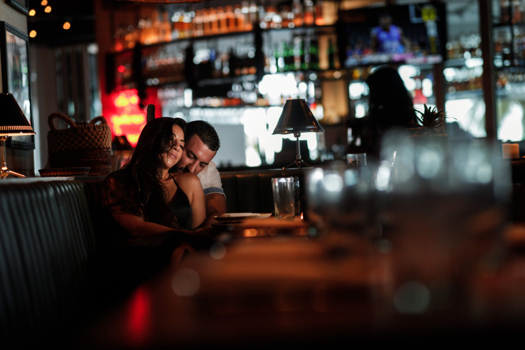 Engaged couple snuggles in their favorite restaurant during their engagement session in Fort Lauderdale