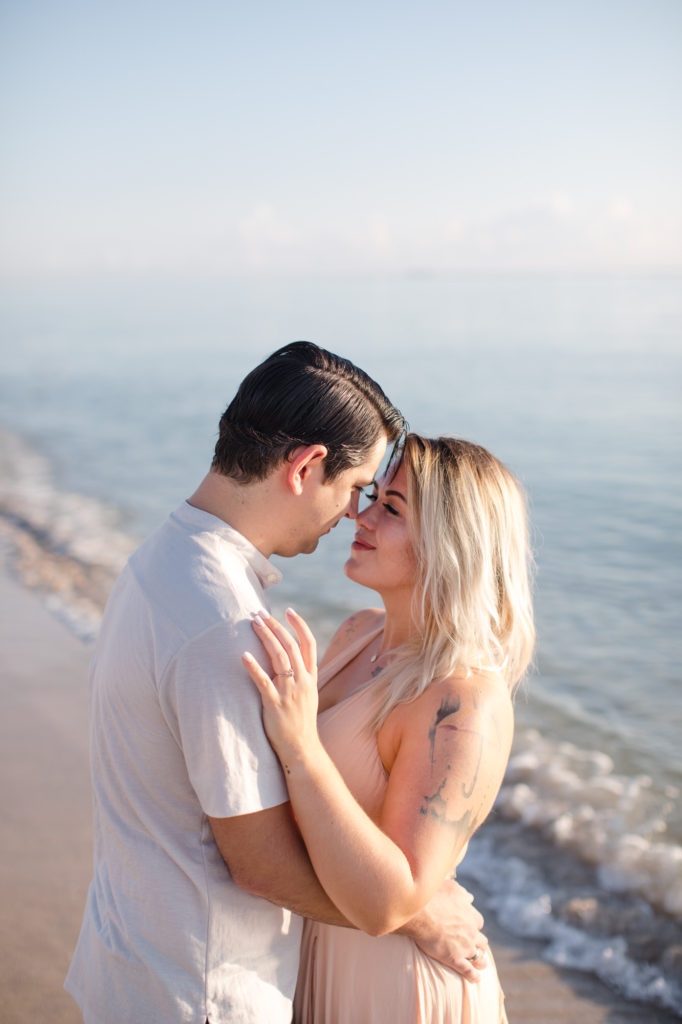 Couple poses near the water on Hollywood beach during their engagement session 