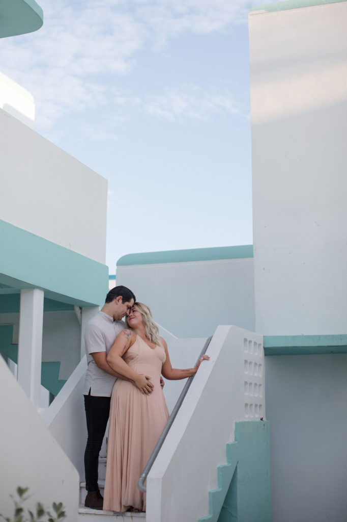 Couple poses on the stairs of an old art deco hotel at Hollywood Beach 