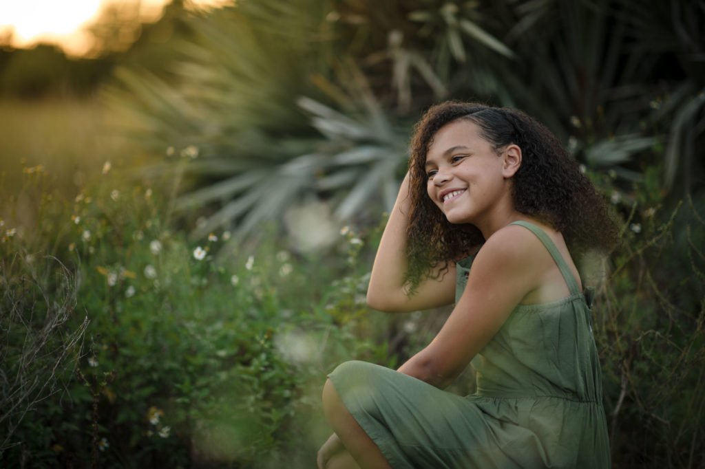 Young girl in green dress poses in grass during her Boca Raton family session