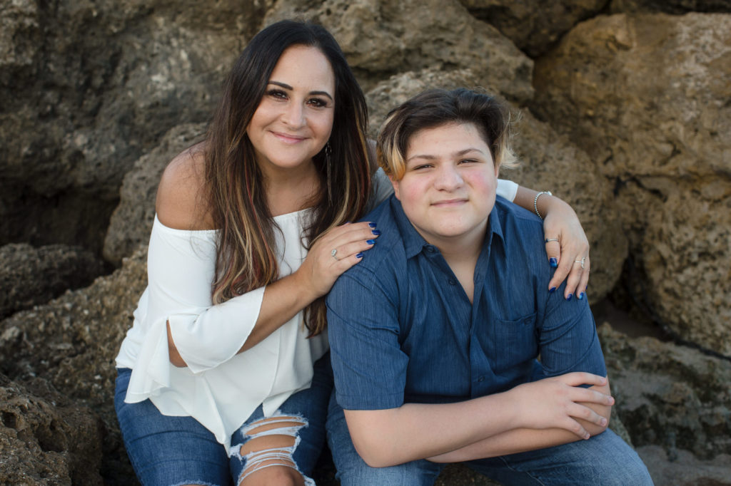 Mom hugs her son on the rocks of Deerfield Beach during their family session