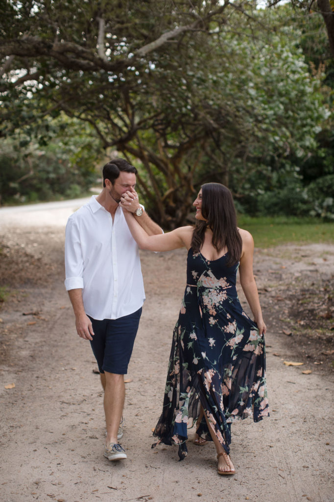 Man kisses his fiance's hand during their engagement session at a Fort Lauderdale park