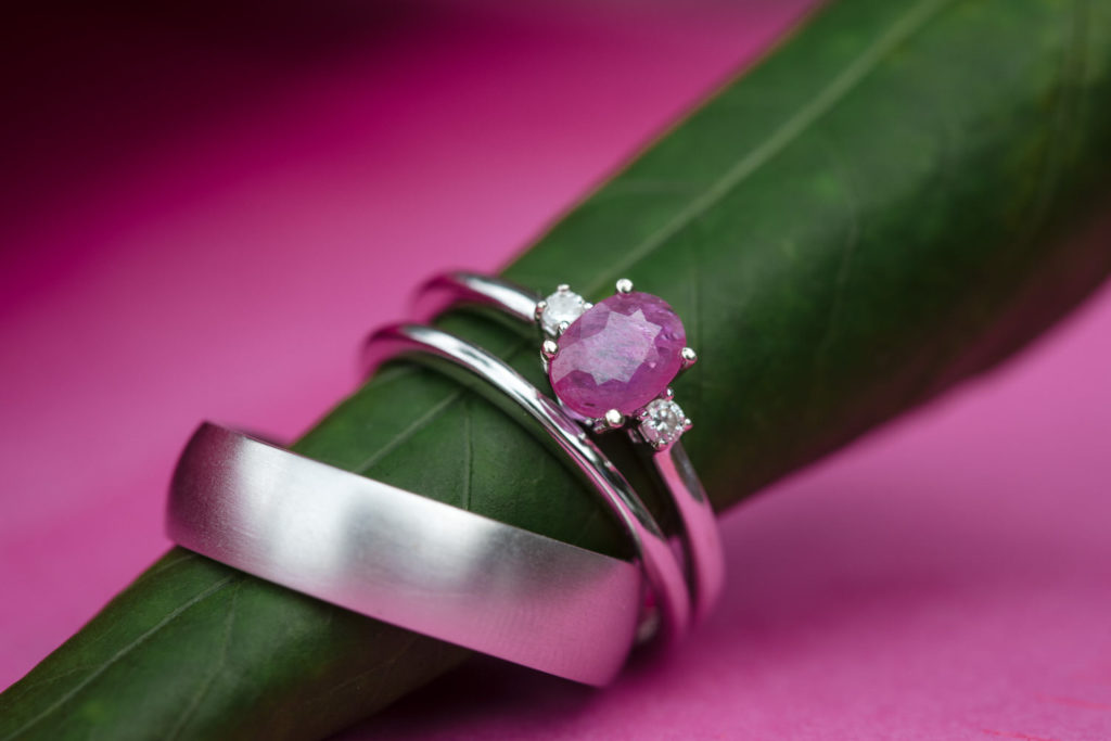 Pink sapphire engagement ring from Midwinter Co and wedding bands on a bright pink background