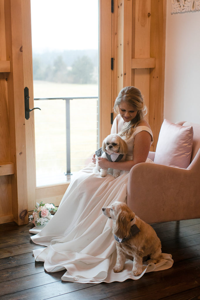 Bride sits on a pink chair near the window in the getting ready suite at Chickadee Hill Farms in North Carolina
