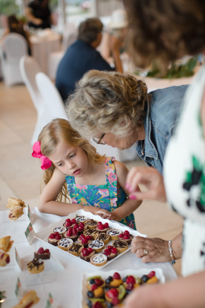 Little girl looks at sweets and desserts as they're being set up at a wedding reception