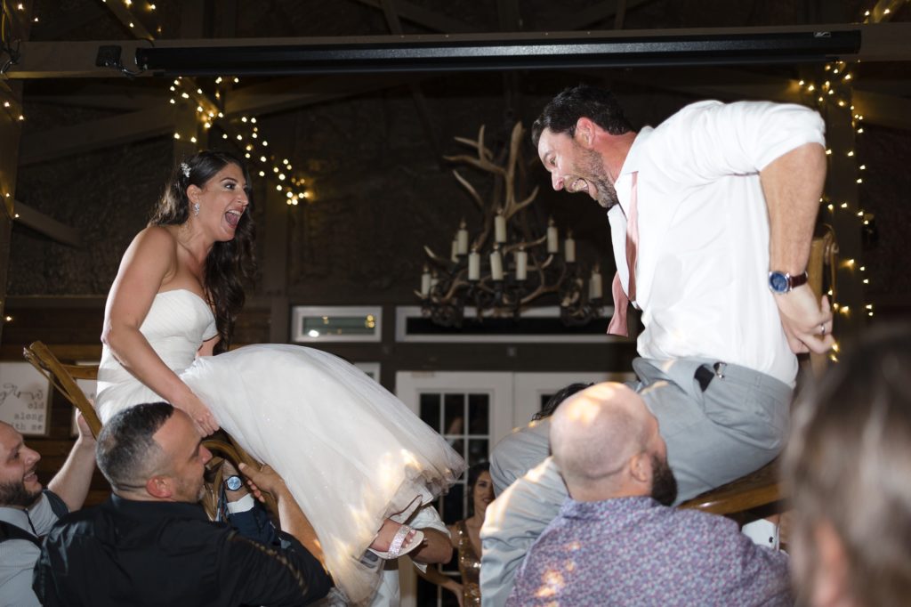 Bride and groom are tossed in chairs for a hora at Ever After Farms