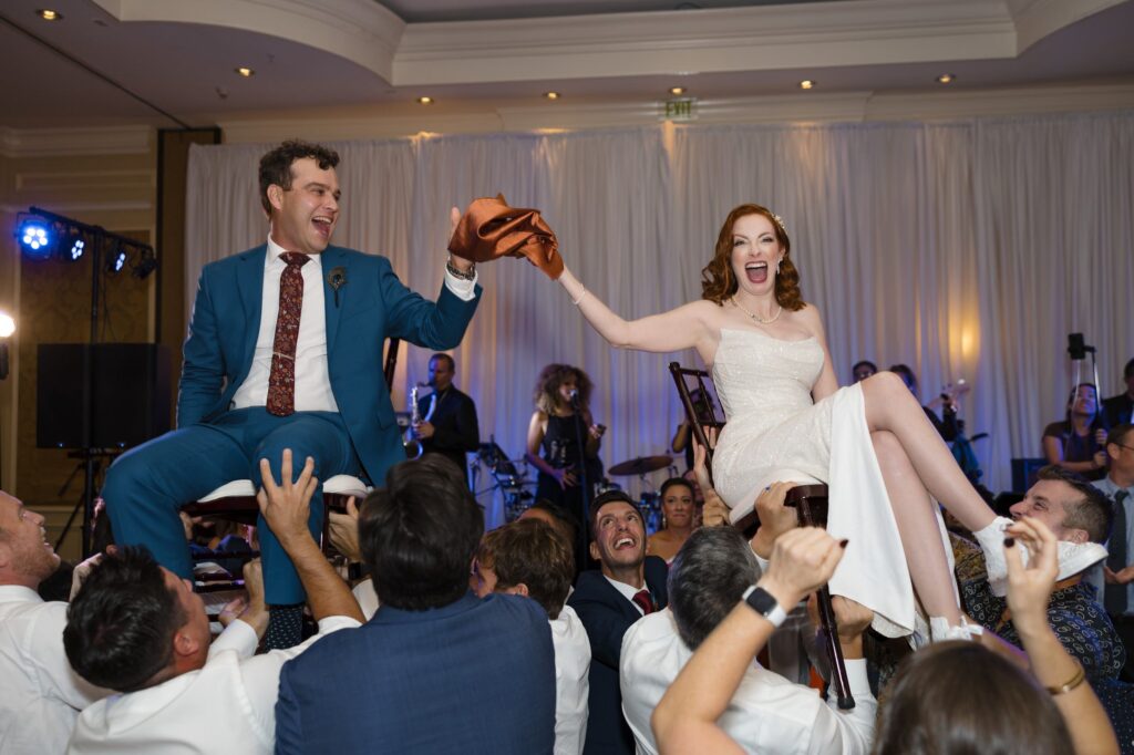 Photo of the bride and groom in chairs during their hora at their Jewish wedding at the Ritz Carlton Coconut grove