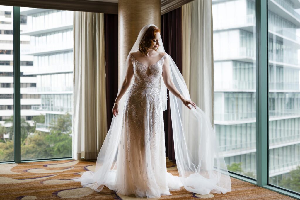 Bride poses for photos in her art deco inspired dress in a corner suite of the Ritz Carlton Coconut Grove